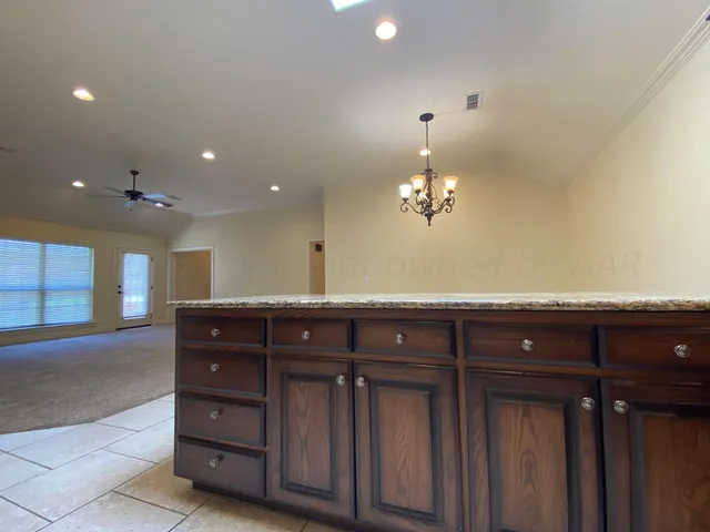 a view of an empty room with a chandelier fan