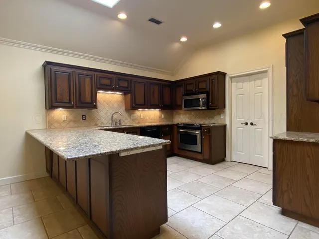 a kitchen with granite countertop a stove a microwave a sink a refrigerator and island