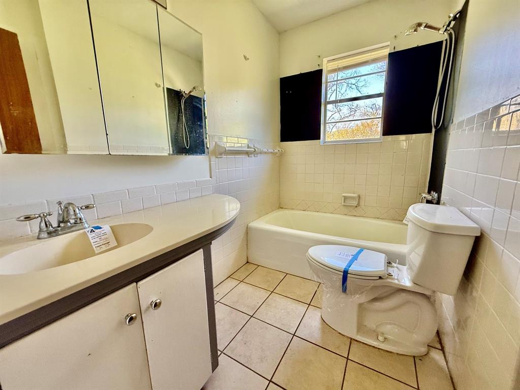 1114 Davis Street Cleburne, TX 76033 - Photo 6 of 17 a bathroom with a sink a toilet and mirror