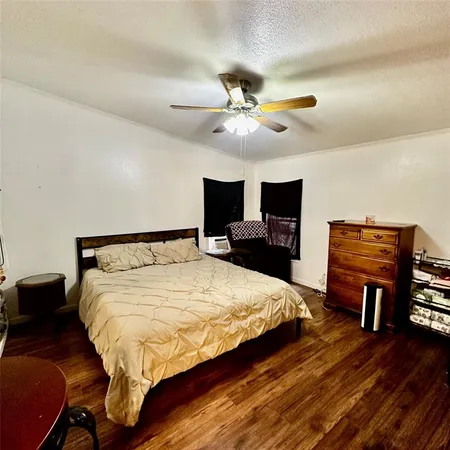 a spacious bedroom with a bed a dresser and a chandelier