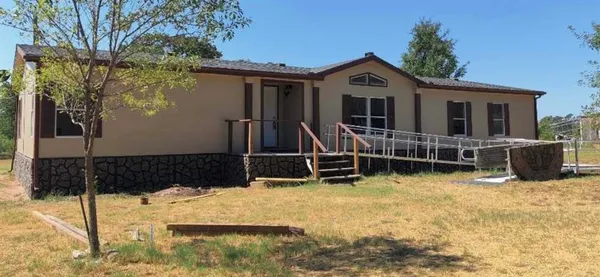 a view of a house with wooden walls and a yard