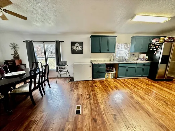 a large kitchen with stainless steel appliances a stove a sink dishwasher a dining table and chair with wooden floor