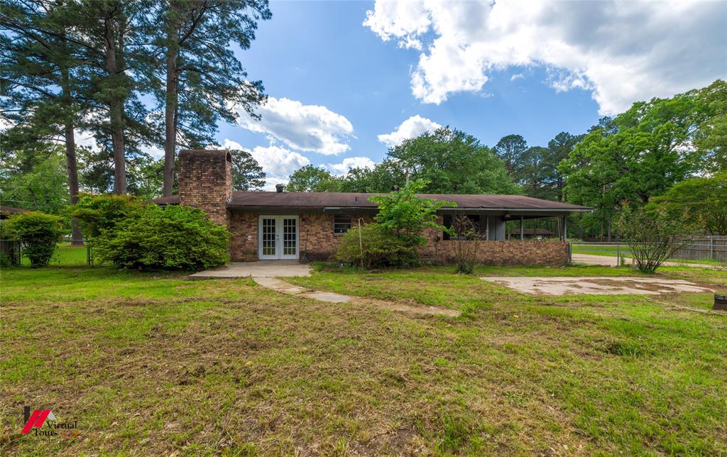 423 11th Street Northeast Springhill, LA 71075 - Photo 6 of 24 Brick exterior residence featuring a prominent stone chimney, white French doors, and a covered front porch