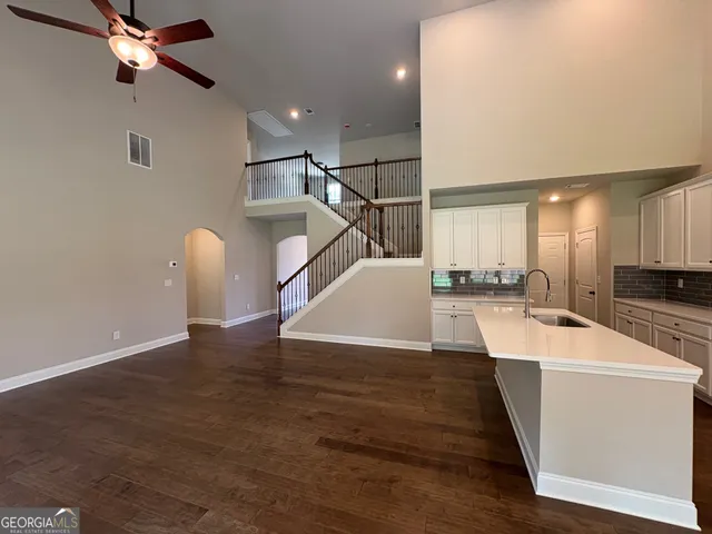 a view of a kitchen with kitchen island stainless steel appliances wooden floor and living room view