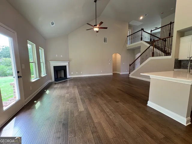 a view of a room with wooden floor a ceiling fan and windows