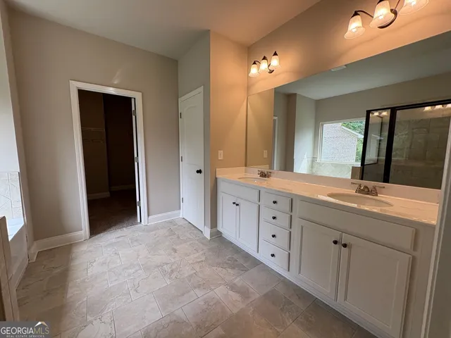 a spacious bathroom with a double vanity sink a large mirror and a shower