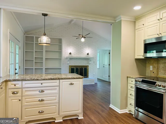 an empty room with wooden floor fireplace and windows