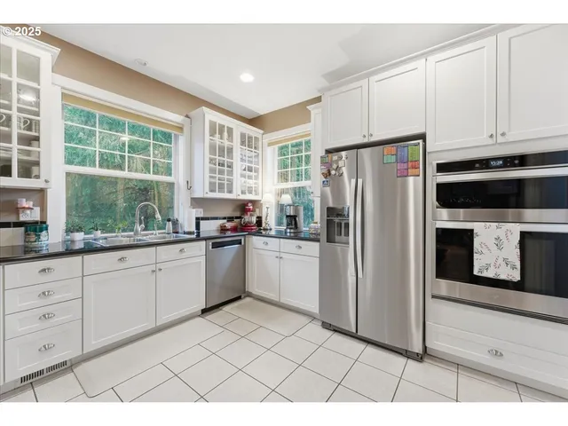 a kitchen with a refrigerator a stove top oven and white cabinets
