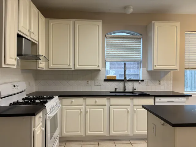 a kitchen with granite countertop a sink a stove and cabinets