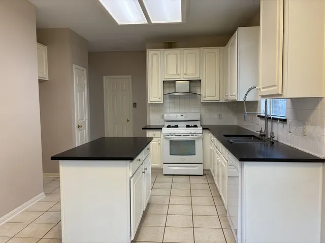 a kitchen with granite countertop a sink stove and cabinets