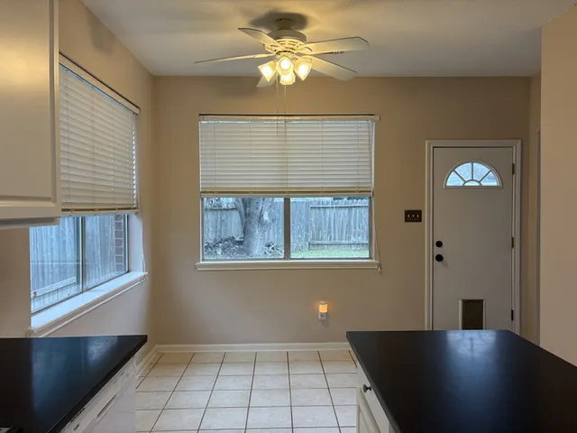 a view of an empty room with window and chandelier fan
