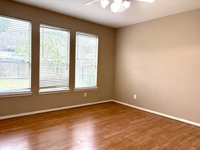 an empty room with wooden floor and windows