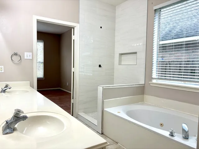 a bathroom with a tub a sink and a window