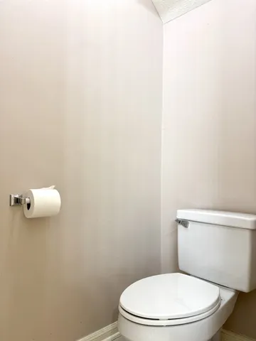 a white toilet sitting next to a white wall