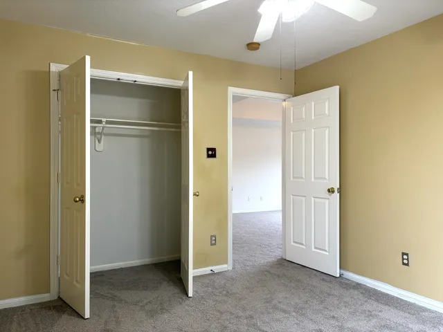 a view of an empty room with closet and a bathroom