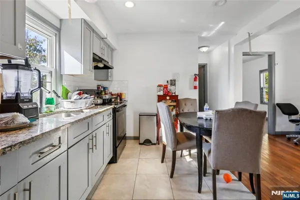 a dining hall with stainless steel appliances granite countertop a dining table chairs and a refrigerator