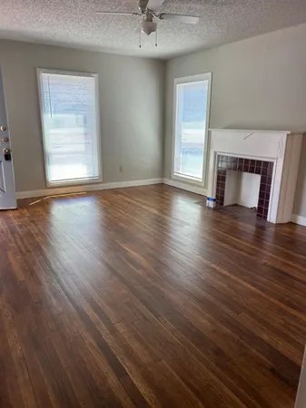 an empty room with wooden floor cabinet and windows