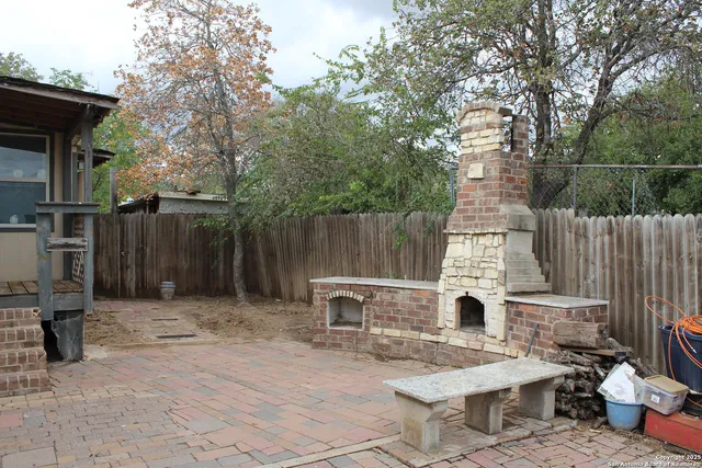 a backyard of a house with barbeque oven and outdoor seating