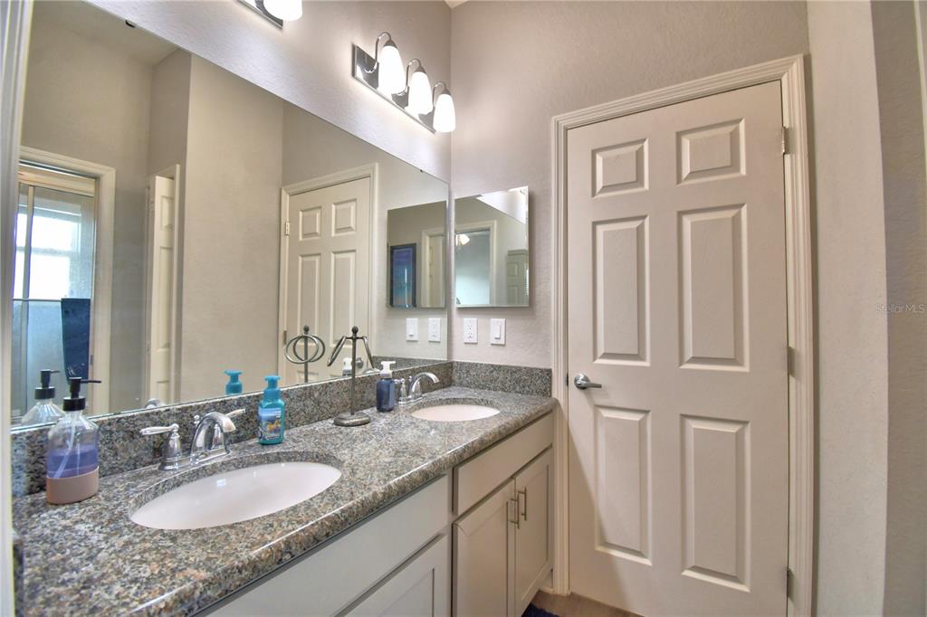 4340 Reding Way Lakeland, FL 33813 - Photo 32 of 63 a bathroom with a granite countertop double vanity sink a mirror and a vanity