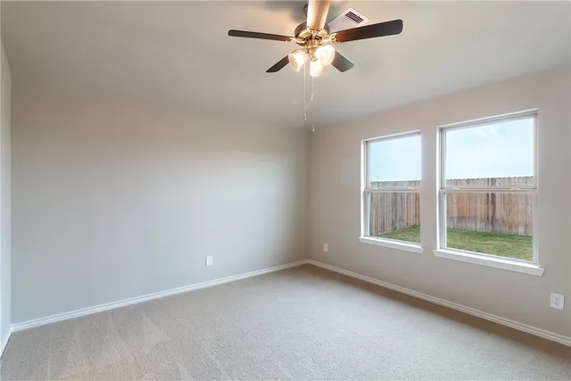 an empty room with a window and a fan