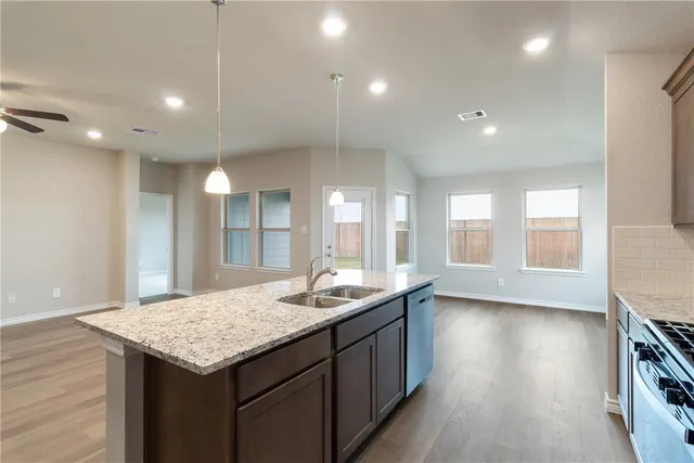 a kitchen with granite countertop kitchen island a sink appliances and a counter space