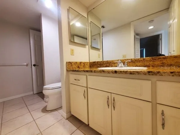 a bathroom with a granite countertop sink a toilet and a mirror