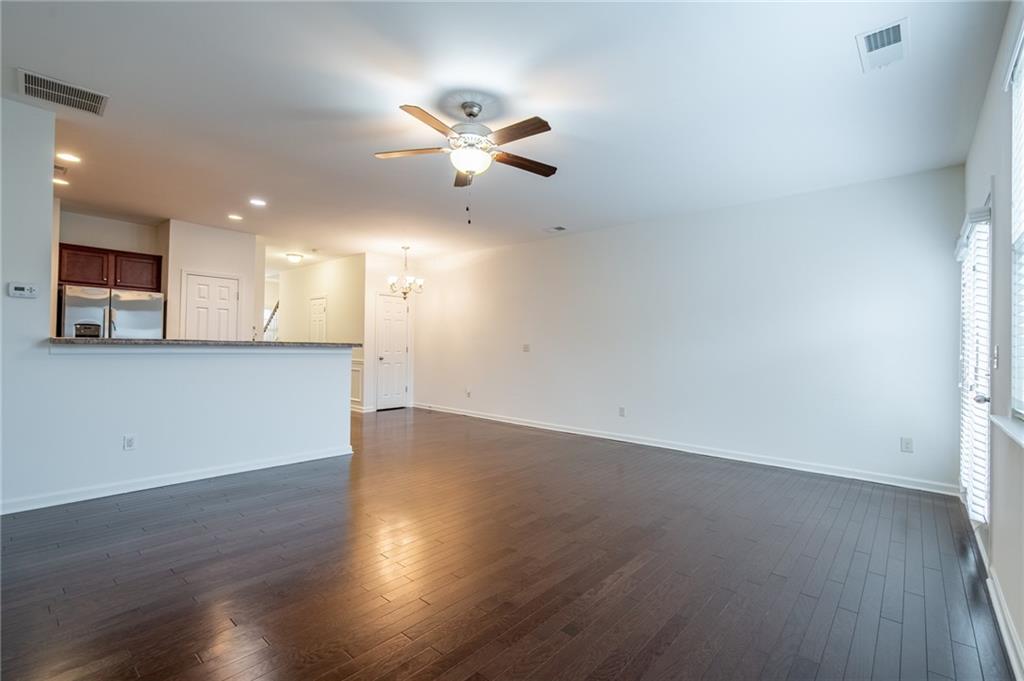 3207 Cyrus Point Lane Kennesaw, GA 30152 - Photo 4 of 24 an empty room with wooden floor a ceiling fan and kitchen view