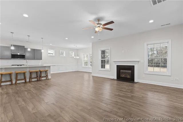 a large white kitchen with a sink dishwasher a stove and a refrigerator with wooden floor