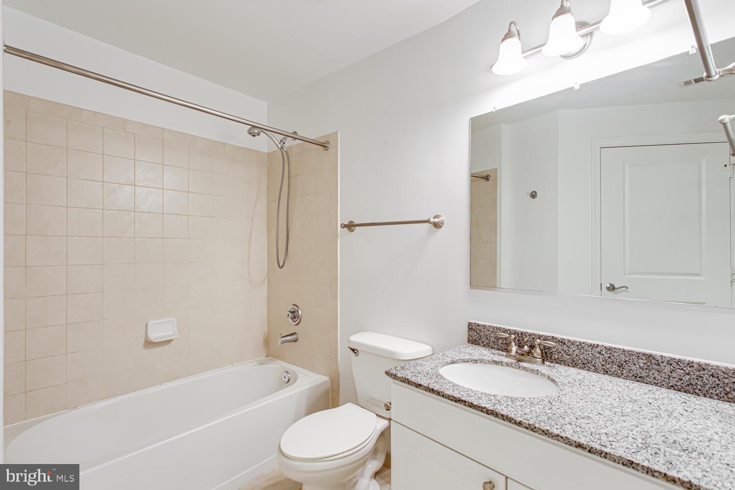3650 South Glebe Road, Unit 239 Arlington, VA 22202 - Photo 24 of 38 a bathroom with a granite countertop bathtub shower sink vanity mirror and toilet