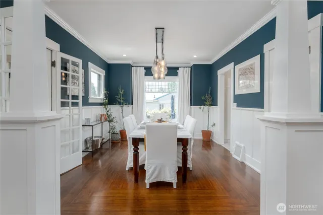 a dining room with wooden floor a chandelier a glass table and chairs
