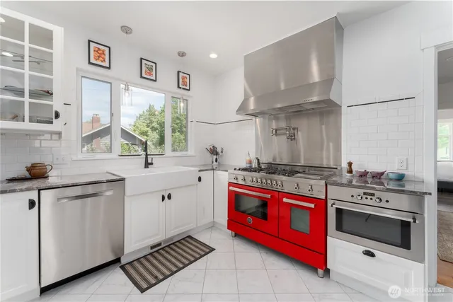 a kitchen with stainless steel appliances a stove and white cabinets