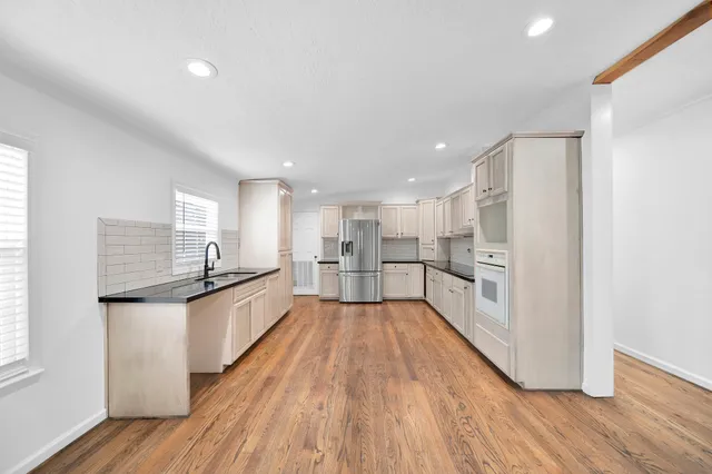 a large white kitchen with wooden floors and stainless steel appliances