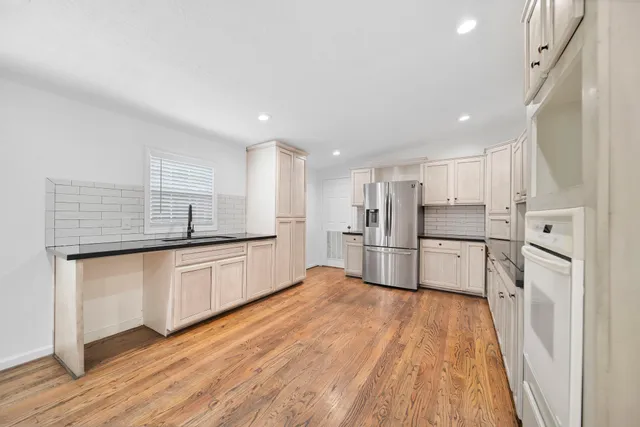 a large kitchen with cabinets wooden floor and stainless steel appliances