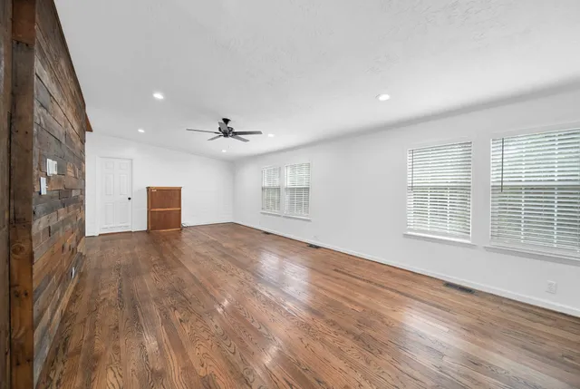 a view of an empty room with wooden floor and a window