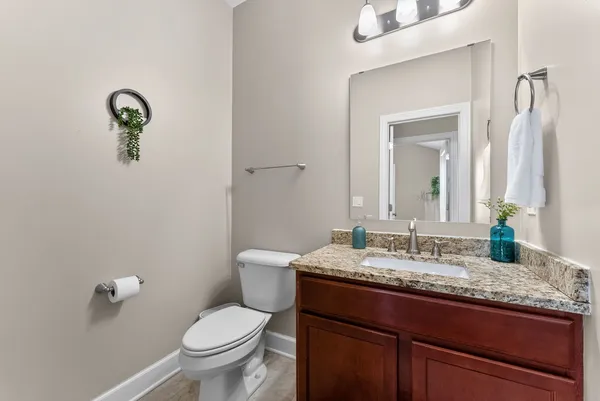 a bathroom with a granite countertop toilet sink and mirror