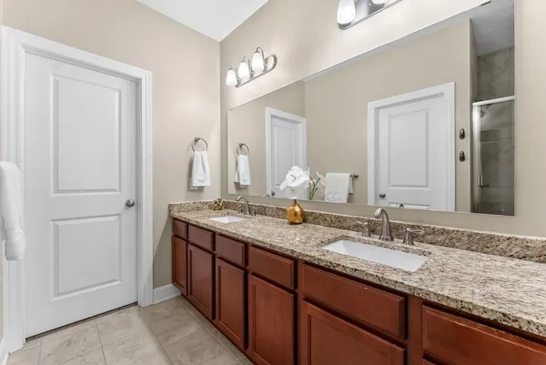 a bathroom with a granite countertop double vanity sink and a mirror
