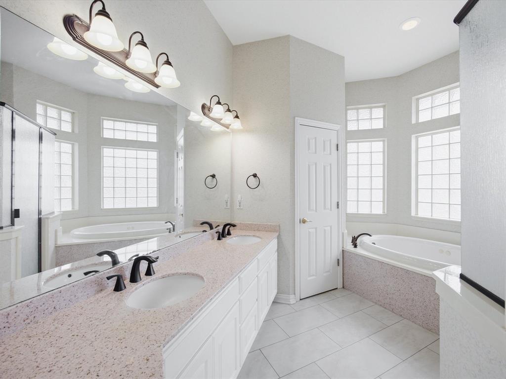 10106 Ravenswood Road Granbury, TX 76049 - Photo 13 of 39 a bathroom with a tub a double vanity sink a window and mirror