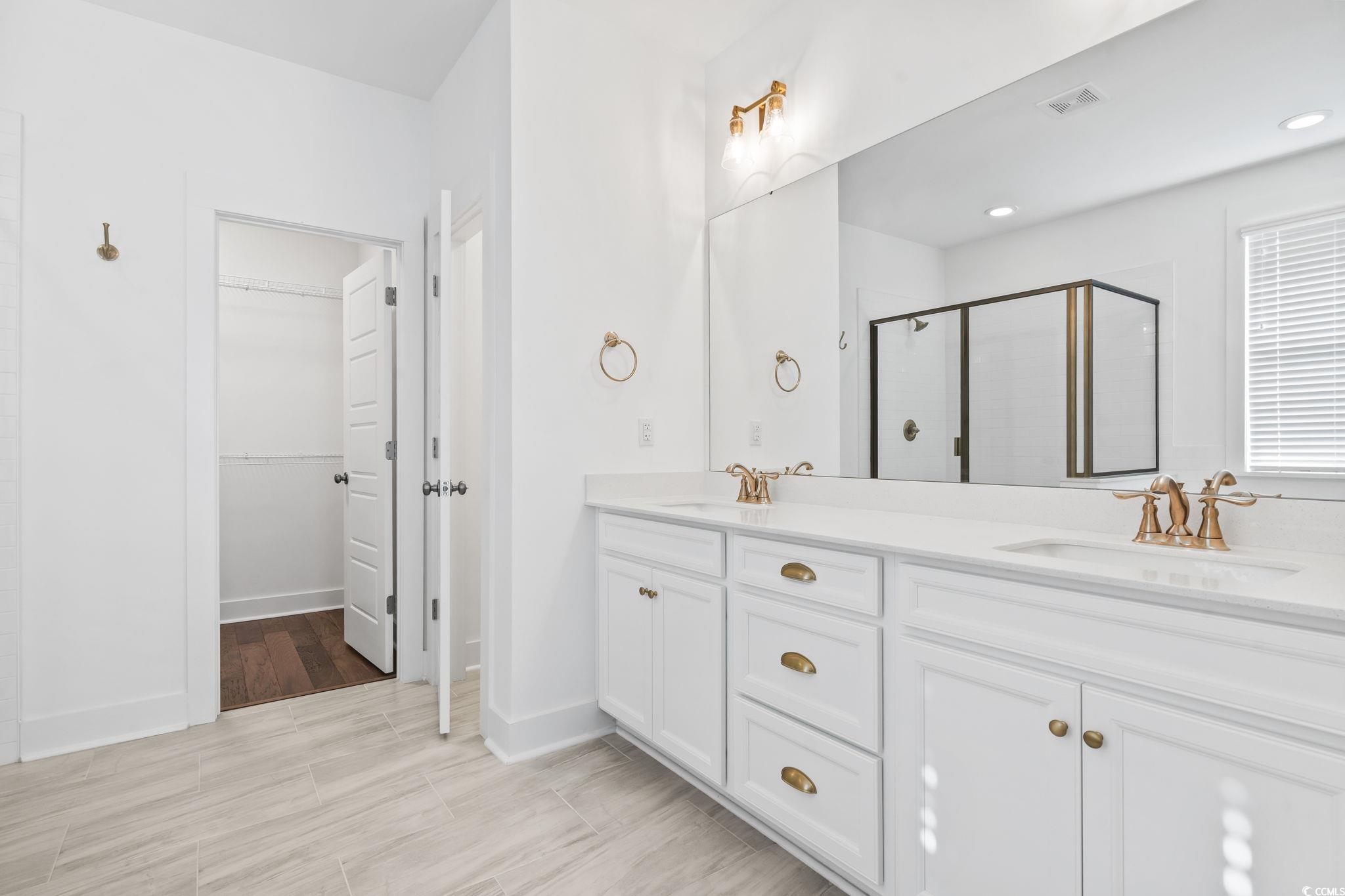 1524 Sayebrook Parkway Myrtle Beach, SC 29588 - Photo 22 of 40 Bathroom featuring a shower stall, a spacious closet, double vanity, and wood finish floors