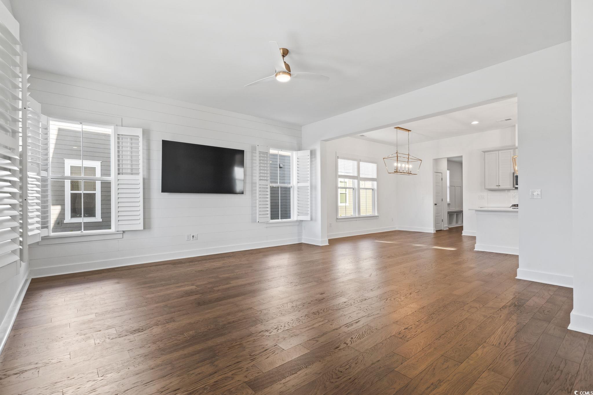 1524 Sayebrook Parkway Myrtle Beach, SC 29588 - Photo 7 of 40 Unfurnished living room featuring dark wood-style floors, ceiling fan, wood walls, and a chandelier