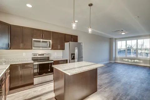 a kitchen with stainless steel appliances granite countertop a refrigerator a sink a stove a microwave and island