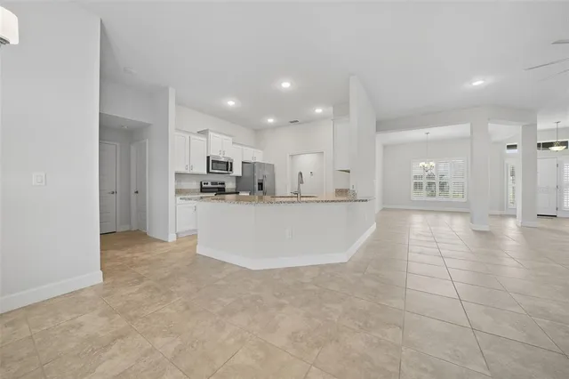 a view of a kitchen with kitchen island white cabinets and stainless steel appliances