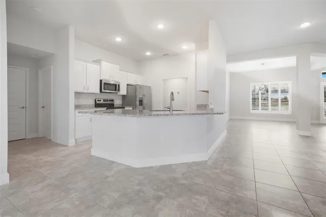 a large kitchen with kitchen island a large counter top stainless steel appliances and cabinets