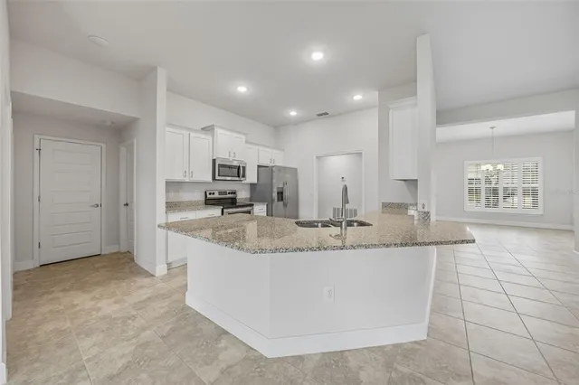 a kitchen with granite countertop a sink stove and refrigerator