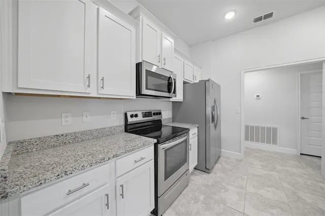 a kitchen with granite countertop white cabinets and white appliances