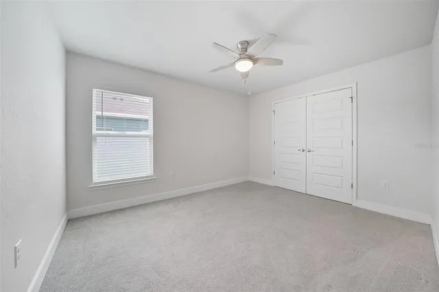 an empty room with windows and ceiling fan