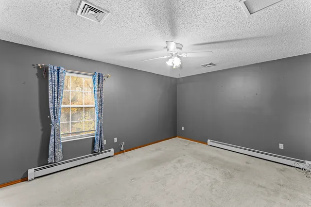 an empty room with windows and fan