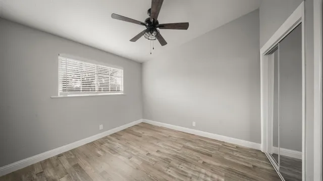 a view of an empty room with a window and wooden floor