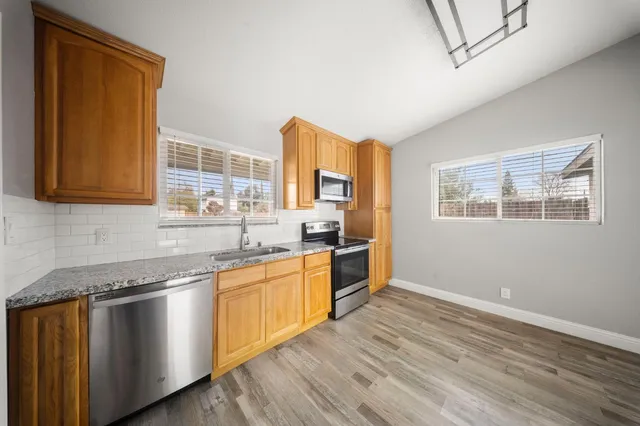 a kitchen with stainless steel appliances granite countertop a refrigerator a stove top oven a sink and dishwasher