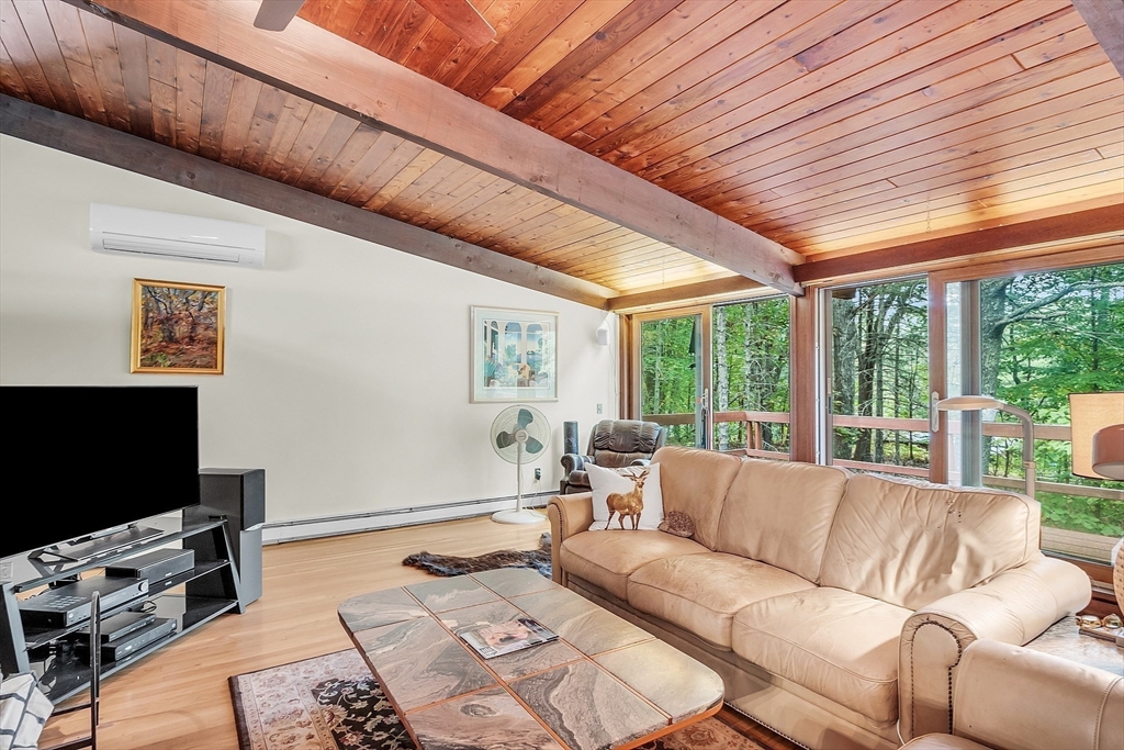 191 Heald Road Carlisle, MA 01741 - Photo 10 of 32 a living room with furniture a flat screen tv and a floor to ceiling window