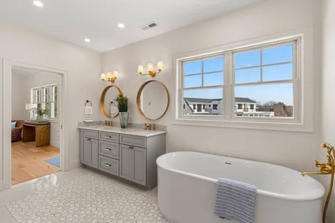 a bathroom with a bathtub a mirror a sink and a window